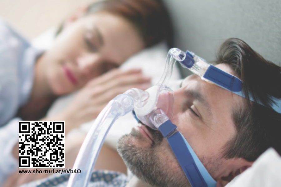 Pärchen schläft im Bett, Mann trägt CPAP Maske