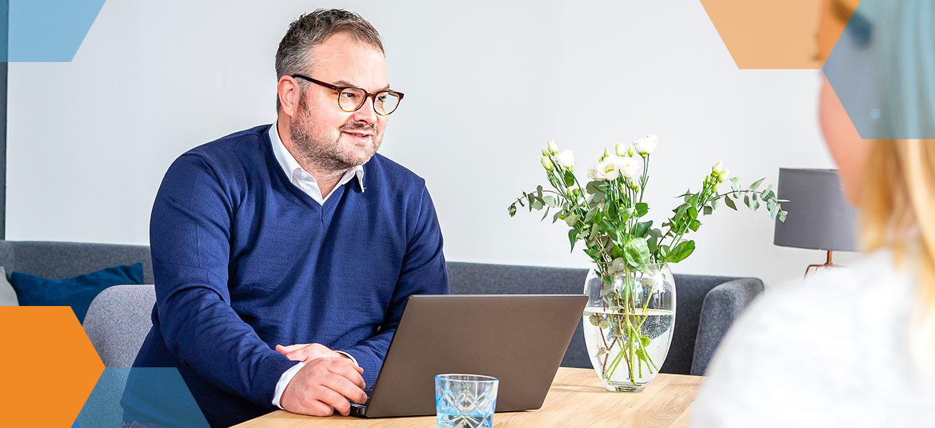 Kollege arbeitet mit Laptop am Meetingstisch