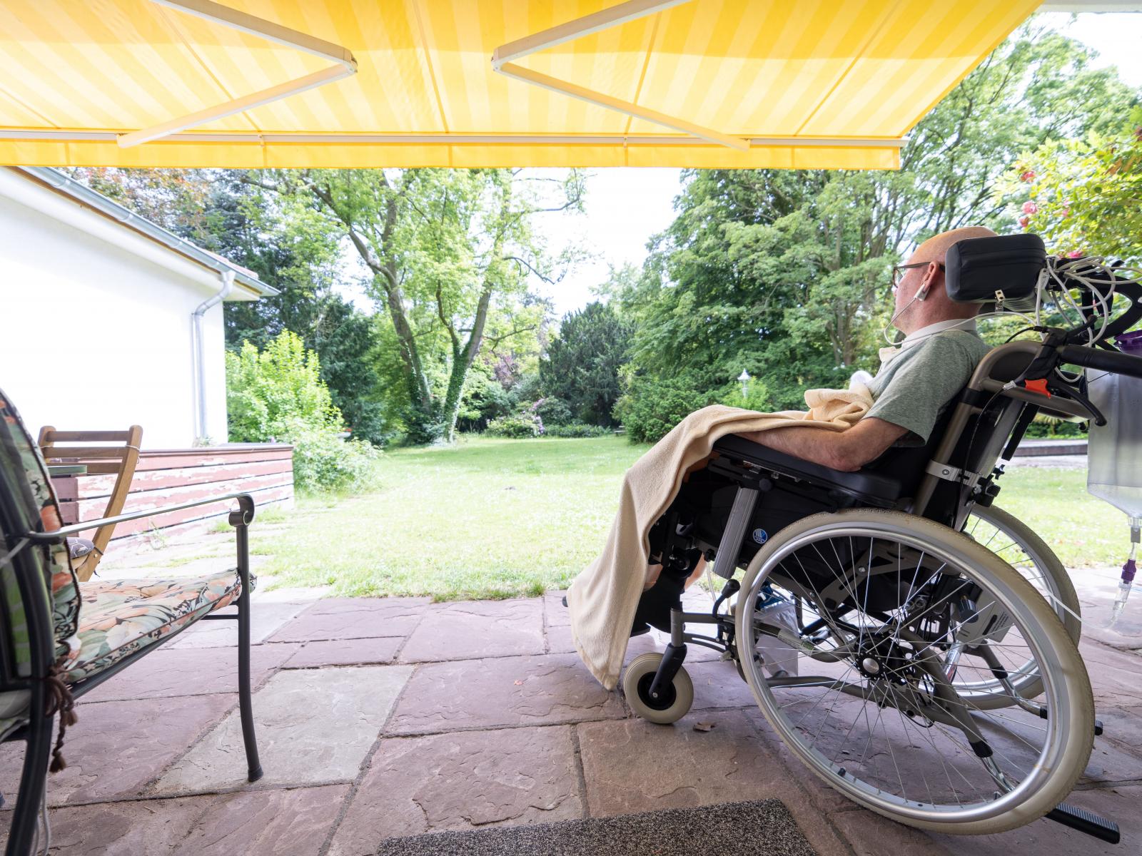 IC_Home_Standort_Koeln_Mann_im_Rollstuhl_guckt_von_der_terrasse_in-den-gruenen-garten