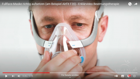 Person zeigt, wie eine Fullface-Maske richtig aufgesetzt wird